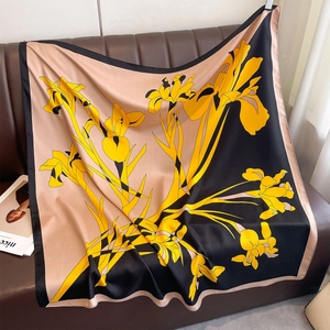 Detailed view of the yellow iris floral print on a luxurious silk-feel large square scarf