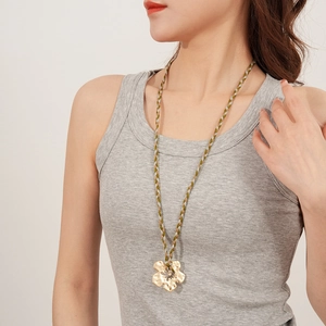 Detail of a handmade golden flower pendant on a brown and olive woven drawstring necklace