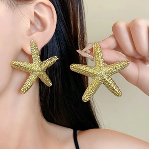 Close-up of vintage golden starfish earrings with textured grain finish on a model