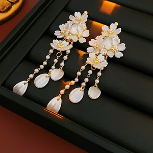Détail de boucles d'oreilles cerisier avec de longs glands en perles et accents dorés
