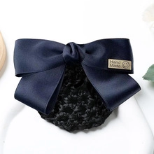 Detail of navy blue satin bow hair clip with mesh net and Hand Made label for flight attendants
