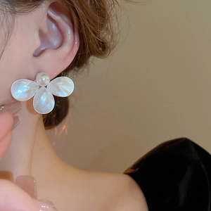 Detail view of flower stud earring with white mother-of-pearl petals and pearl center