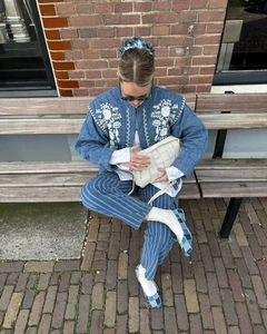 Outdoor street style view of a retro blue denim puffer jacket with embroidery details