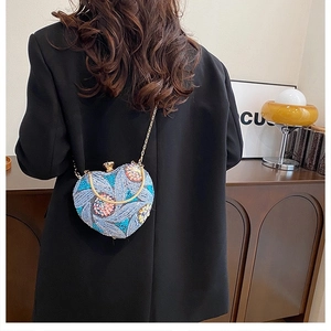 Detail of heart-shaped sequin clutch with beads worn over a black blazer for women