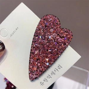 Detail showing a heart-shaped hair clip with shimmering pink Czech rhinestones