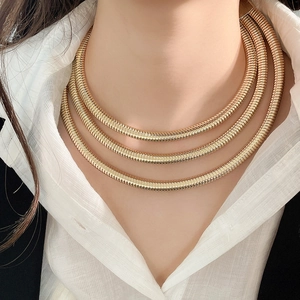 Detailed close-up of triple-layered golden snake chain necklace with high polish finish