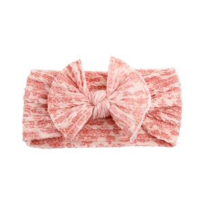 Detail of pink knitted baby headband featuring a soft double-layer large bow design