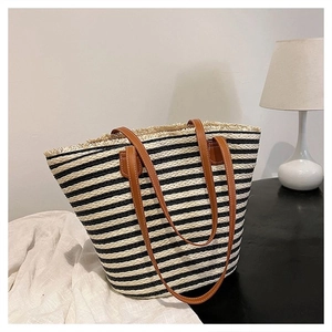 Detail of striped straw tote bag featuring brown leather straps and fringed edge design