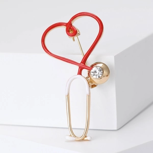 Macro detail of gold stethoscope brooch with red enamel heart and sparkling rhinestone