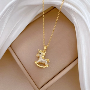 Gold plated rocking horse necklace with sparkling crystals on silk background