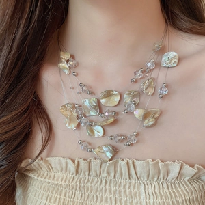 Detail of layered bohemian necklace with natural shell slices and crystal beads on a model