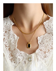 Detail of a double-layered gold titanium necklace with a black rectangular pendant on neck