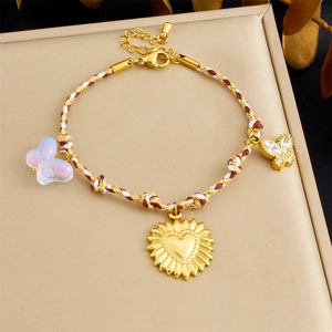 Close-up of woven bracelet with heart sun and butterfly charms on jewelry box