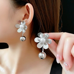 Détail de boucles d'oreilles fleur argentée avec perle, design six pétales et bille