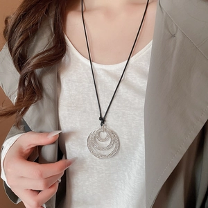 Detailed view of triple-layered circular crystal pendant on a long black leather cord