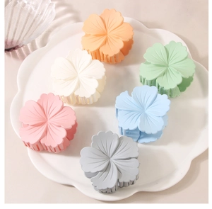 Set of six matte flower-shaped hair claws in macaron colors displayed on a white tray