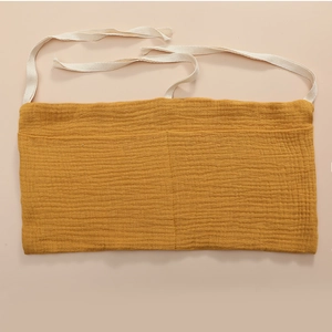 Detailed texture of mustard yellow cotton gauze bedside storage bag with two large pockets