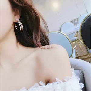 Close-up of three-layered gold hoop earrings with sparkling rhinestones on model