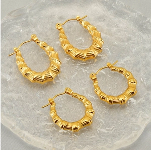 Dettaglio di orecchini a cerchio intrecciati e texture bambù placcati oro 18 carati