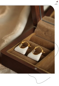 Detailed view of geometric cream enamel and gold plated triangle hoop earrings