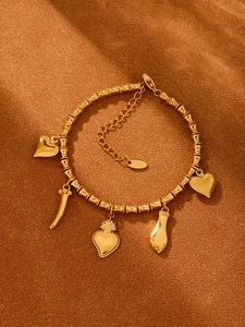 Details des 18k vergoldeten Armbands mit fünf Anhängern auf orangefarbenem Stoff