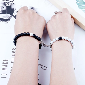 Detail of 8mm natural stone couple bracelets with magnetic heart clasp on magazine background