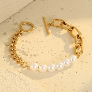 Elegante pulsera de perlas doradas con cierre OT y colgante de corazón sobre piedra