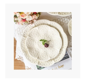 Macro view of embossed floral patterns on cream-colored ceramic plates for tea time