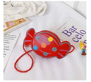 Détail d'un sac à bandoulière enfant en forme de bonbon rouge avec des pois colorés et cordon