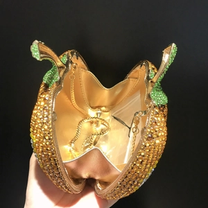 Dettaglio della pochette a zucca aperta con cristalli arancioni e fodera dorata