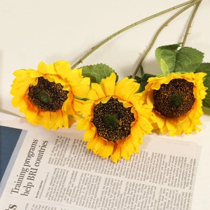 Detailed view of artificial yellow sunflowers with dark centers on newspaper
