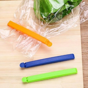 Set of plastic food bag sealing clips in orange, blue and green on a wooden surface
