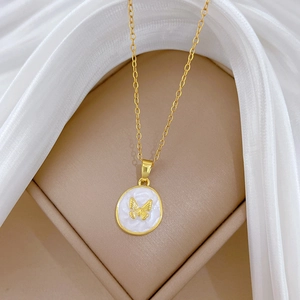 Golden butterfly necklace with round white enamel pendant on white silk fabric background