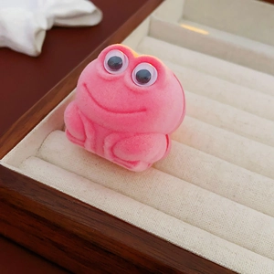 Detailed view of a cute pink frog-shaped velvet ring box on a jewelry display tray