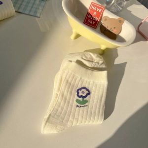 Detail of yellow ribbed cotton socks featuring blue flower embroidery and flower text