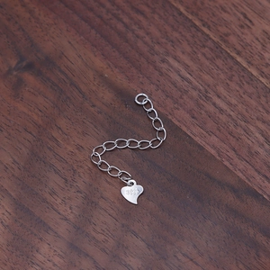 S925 sterling silver extender chain with lobster clasp and heart tag on wood background