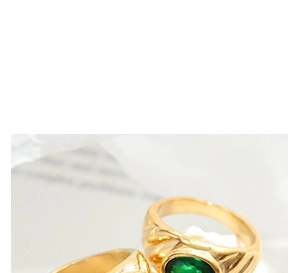 Gros plan détaillé d'une bague vintage dorée avec anneau texturé et une pierre précieuse verte