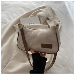 Detailed close-up of beige tweed underarm bag with dark brown leather trim and gold hardware