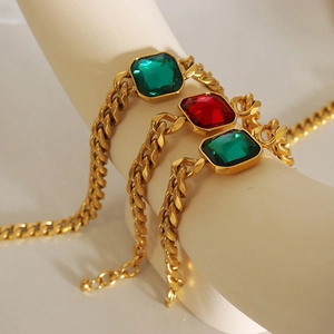 Golden cuban chain bracelet featuring green and red square crystal charms on display