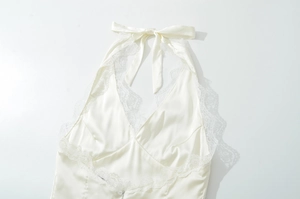 Detailansicht eines weißen Satin-Neckholder-Tops mit Schleife und Spitzenbesatz