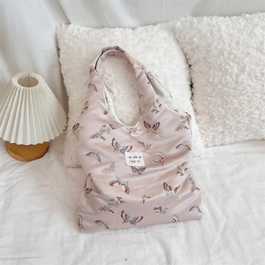 Detail of light pink jacquard tote bag with butterfly prints and brand woven label