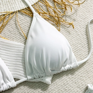 Macro detail of white triangle bikini top with pleated cups on summer beach background