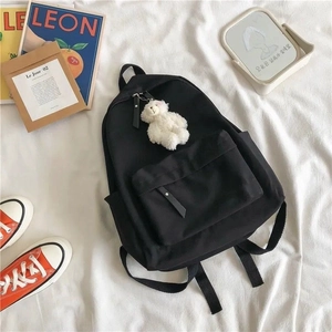 Minimalist black student backpack with cute white bear charm and front utility pocket