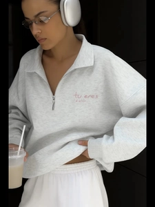 Close-up of light gray half-zip hoodie with pink embroidered text on the chest