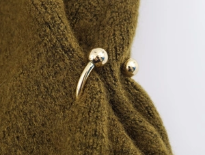 Macro detail of golden metal spherical buckles on mustard yellow knitted fabric texture