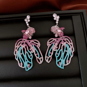 Gros plan de boucles d'oreilles poisson avec cristaux roses et bleus sur cuir noir