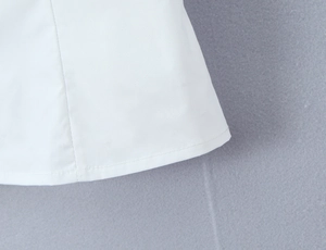 Close-up of clean white woven fabric hem stitching on vintage puff sleeve shirt