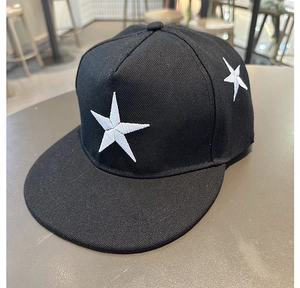 Détail d'une casquette noire à bord plat avec étoiles blanches brodées sur coton sergé