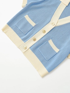 Detail of blue and white knit cardigan featuring textured fabric and gold embossed buttons
