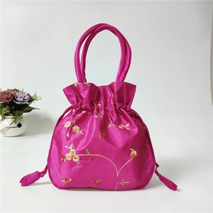 Detailed embroidery of yellow flowers on a rose-red satin drawstring handbag